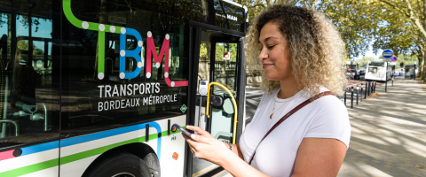 Personne debout devant un bus en train de regarder son téléphone portable.