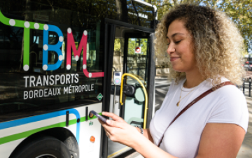 Personne debout devant un bus en train de regarder son téléphone portable.